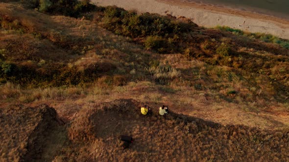 Aerial Footage of Two People Sitting on the Edge of Cliff and Overlooking Bay of Black Sea