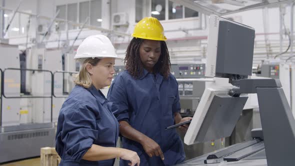 Diverse Female Factory Employees Studying New Machine