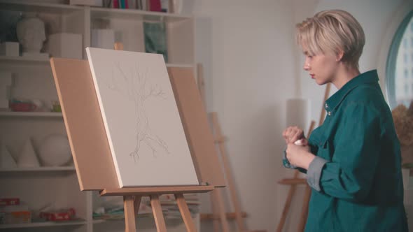 A Young Woman Artist Opening Up a Beige Paint To Color Her Painting