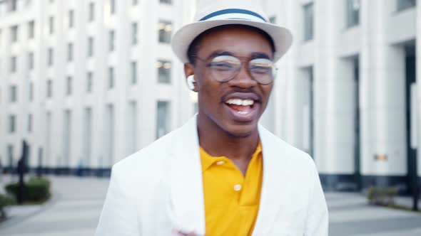 Joyful black performer in glasses and wireless headphones looks