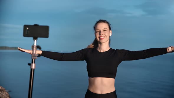 Smiling Female Blogger Shooting Outdoor Training on Beach Use Smartphone