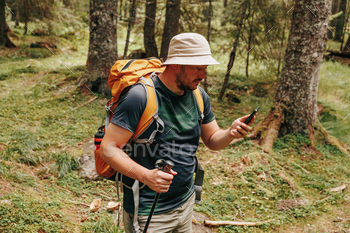 as a young Latino traveler embraces the fusion of hiking and smartphone technology. This captivating image showcases the harmonious