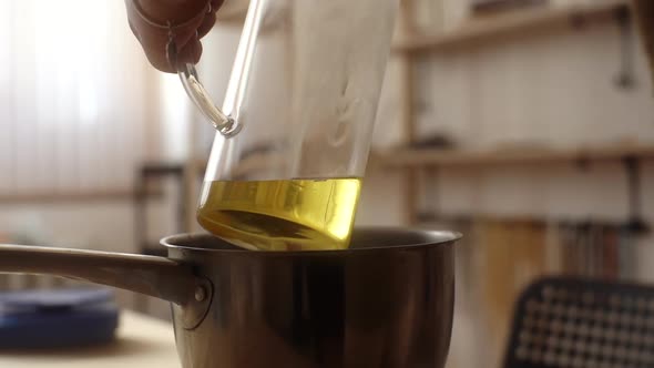 Closeup of Unrecognizable Female Artisan Pouring Melted Wax Into Glass Jar Over Boiling Pan of Steam