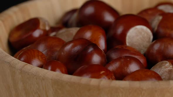 Chestnuts in a Wooden Bowl Rotate on Black Background