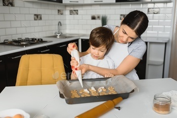Happy mother and child in kitchen preparing cookies