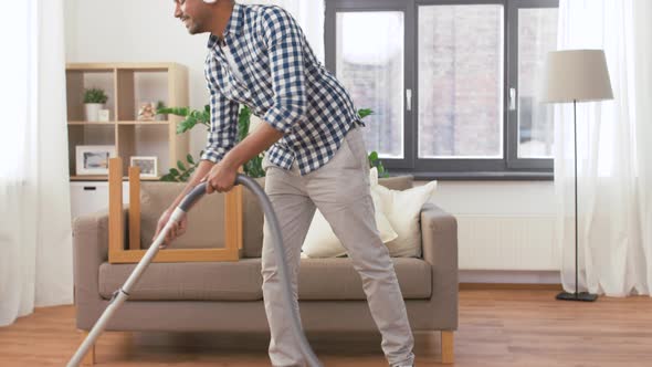 Man in Headphones with Vacuum Cleaner at Home 