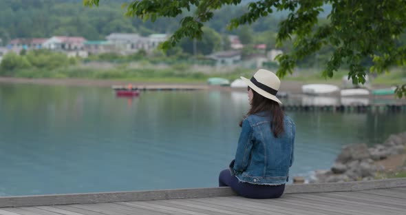 Woman Look at The Beautiful Lake and Sit at The Wooden Floor