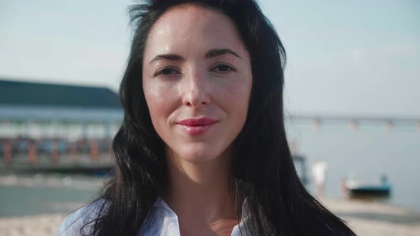 Young Brunette Woman Smiling Cheerful Enjoying Lifestyle Looking at Camera on Calm Beach Sunset