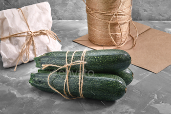 A bunch of zucchini on a gray background with a paper bag for delivery, food delivery, environmental