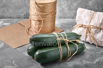 A bunch of zucchini on a gray background with a paper bag for delivery, food delivery, environmental