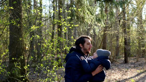 Father in a Blue Hooded Jacket Throws His Young Son