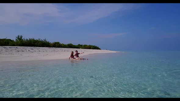 Boy and girl posing on idyllic resort beach lifestyle by blue lagoon with white sandy background of 