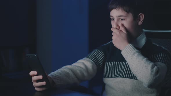 Afraid and Shocked Boy Look at Smartphone Screen Cover Mouth with Hand at Night at Home