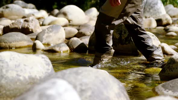 Fly fisherman walking in river on a sunny day