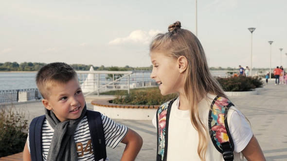 Boy and girl with backpacks walking and talking. Primary