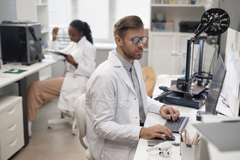 Male Technician Using Computer in 3D Printing Lab