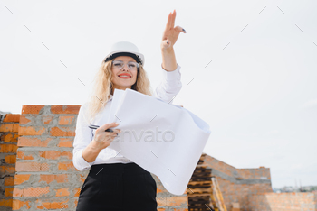 beatiful woman engineer is reviewing the plans of a construction work