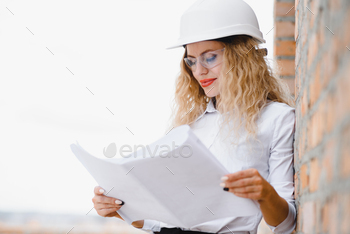 beatiful woman engineer is reviewing the plans of a construction work.