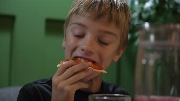 Cute Boy Taking Big Bite of Cheese Pizza at Restaurant