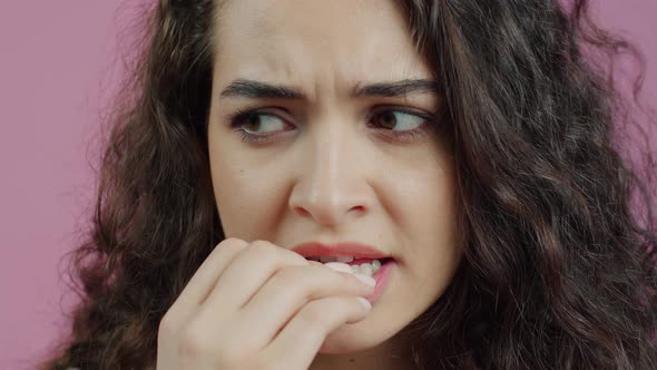 Closeup Portrait of Nervous Young Woman Biting Finger Nails and Looking at Camera