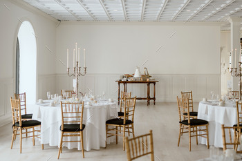 Long hall with white linen, showcasing tables and chairs in modern wedding setup