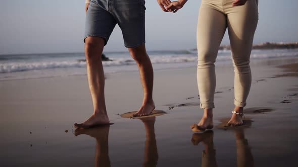 Unrecognizable Young Couple Stepping Together at the Golden Sand at Sea Beach