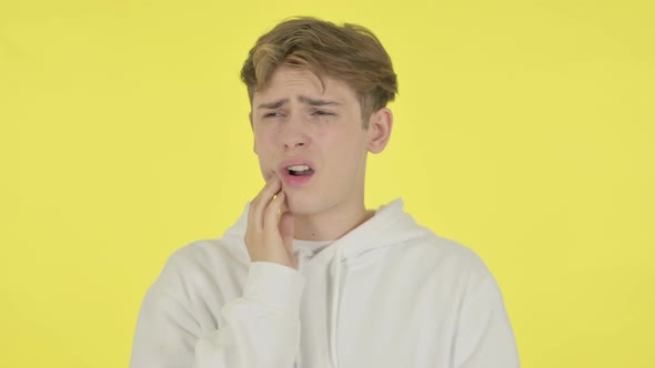 Young Man Having Toothache on Yellow Background