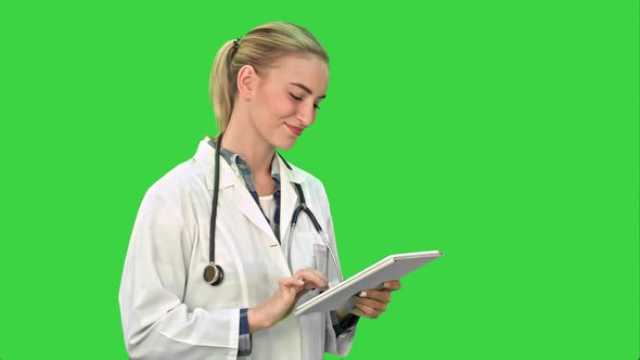 Charming Female Doctor with Stethoscope Smiling While Using Tablet Computer on a Green Screen