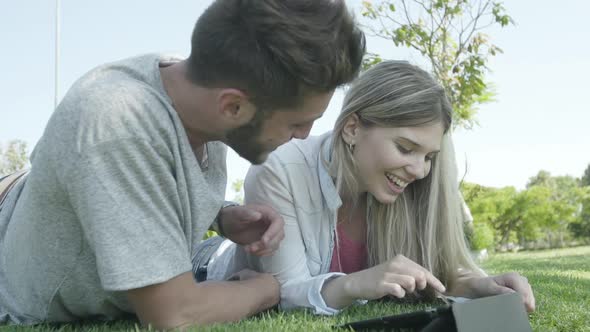 Couple using digital tablet in park