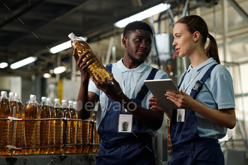 Colleagues checking quality of bottle