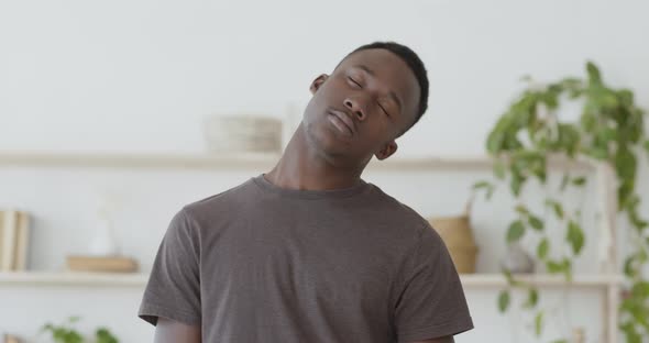 Morning Workout. Young Black Man Warming Up His Neck at Home