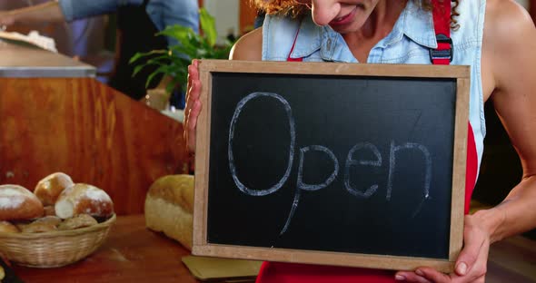 Female staff holding a open sign slate in supermarket