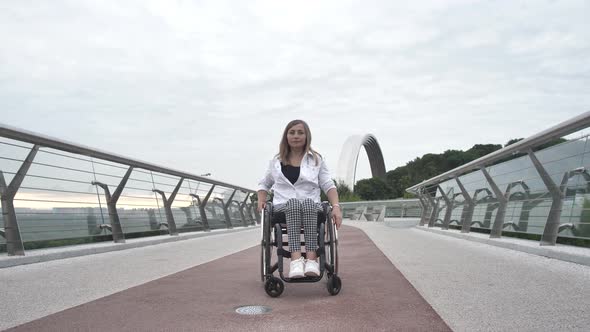 Confident Woman Riding Wheelchair Along Footbridge