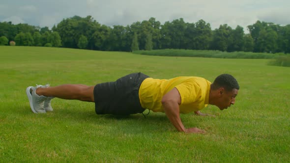 Motivated Sporty Fit African Man Doing Advanced Push Up Exercise in Nature