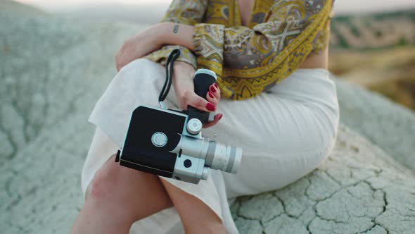 8Mm Vintage Camera Held By a Girl Sitting on the Rock in the Nature