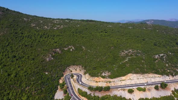 Scenic Aerial View of Asphalt Road and Wooded Mountain Slopes on a Summer Day alt