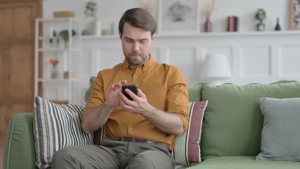 Young Man using Smartphone on Sofa