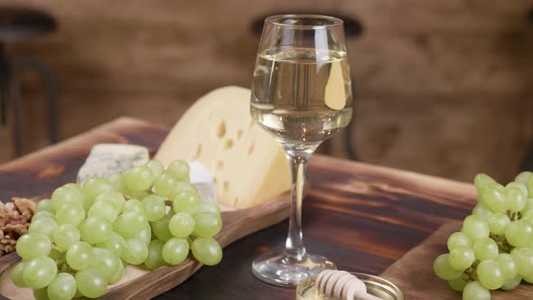 Rotating Composition of Cheese Served with a Glass of Wine and Grapes