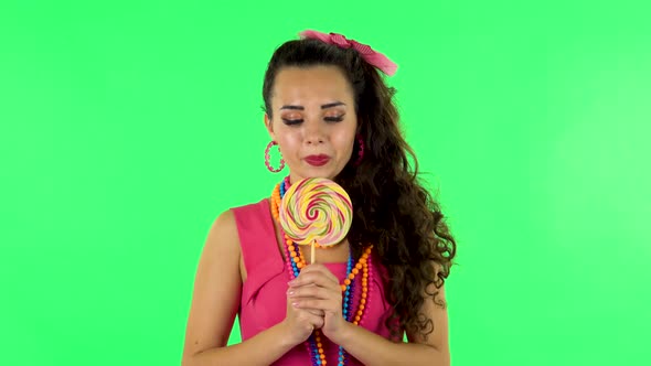 Girl with Great Pleasure Eats a Large Multi-colored Candy While Enjoying