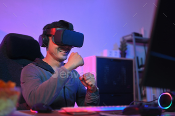 Happy excited man playing boxing game in VR glasses at home with neon led lights