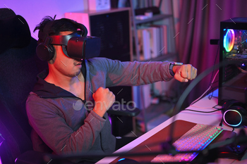 Shot of young man playing boxing game in virtual reality glasses. Entertainment concept