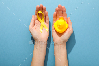 A yellow toy duck with a yellow ribbon