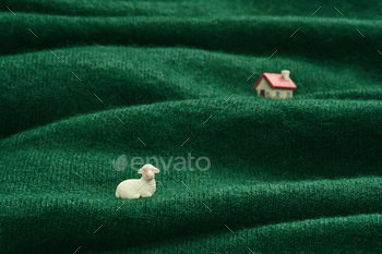 and house figurines on a green wool fabric depicting a pastoral scene.