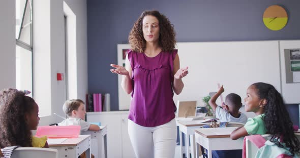 Video of caucasian female school teacher and diverse school children studying in classroom