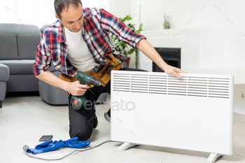 service man with wrench near radiator
