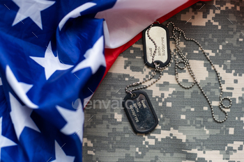 Army tokens on military uniform and USA national flag background.