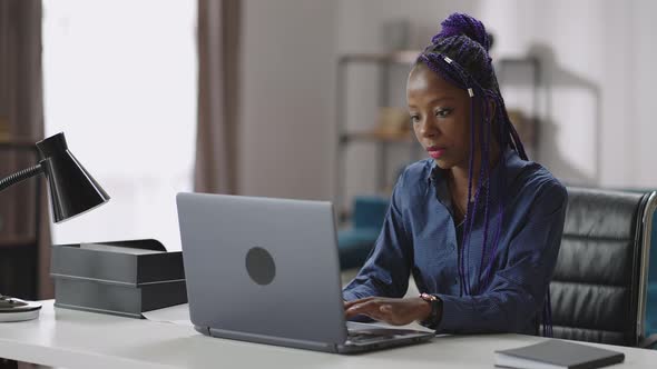 Afroamerican Woman is Working with Laptop Remote Job at Home Young Lady is Sitting at Table and
