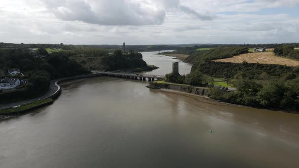 Drone shot of a river estuary with a busy bridge and castle ruins.