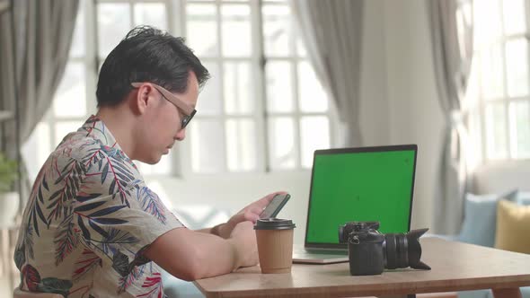Photographer Use Mobile Phone With Green Screen Display Laptop Computer