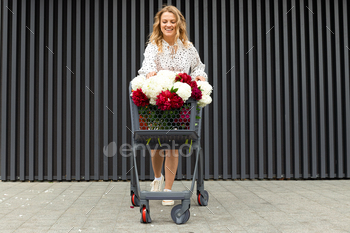 A beautiful girl with a cart with flowers on the street.